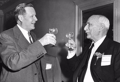 black and white photo of two men in suits toasting