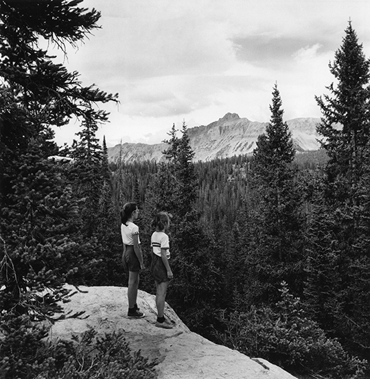 black and white photo of two middle school aged children looking out over a mountain scape