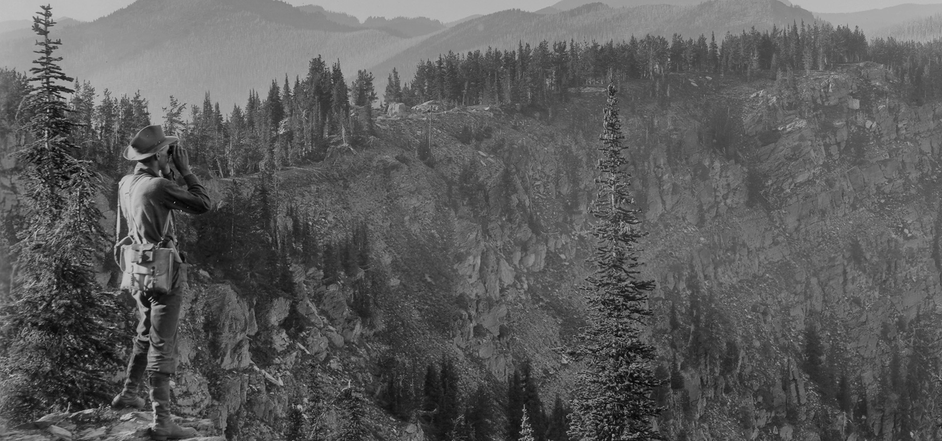 black and white photo of ranger looking over a rocky mountain valley