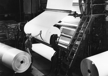 black and white photo of paper rolls on large machine