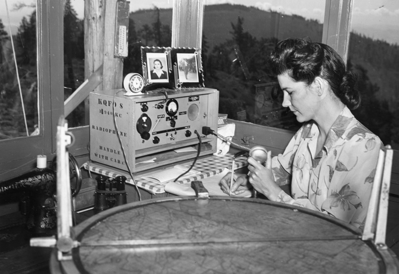 Fire lookout Thelma Duke operates radio at Chase Mountain lookout tower in Oregon.