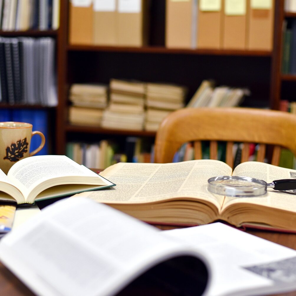 library table covered in open books and magnifying glass