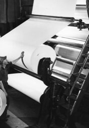black and white photo of paper rolls on large machine